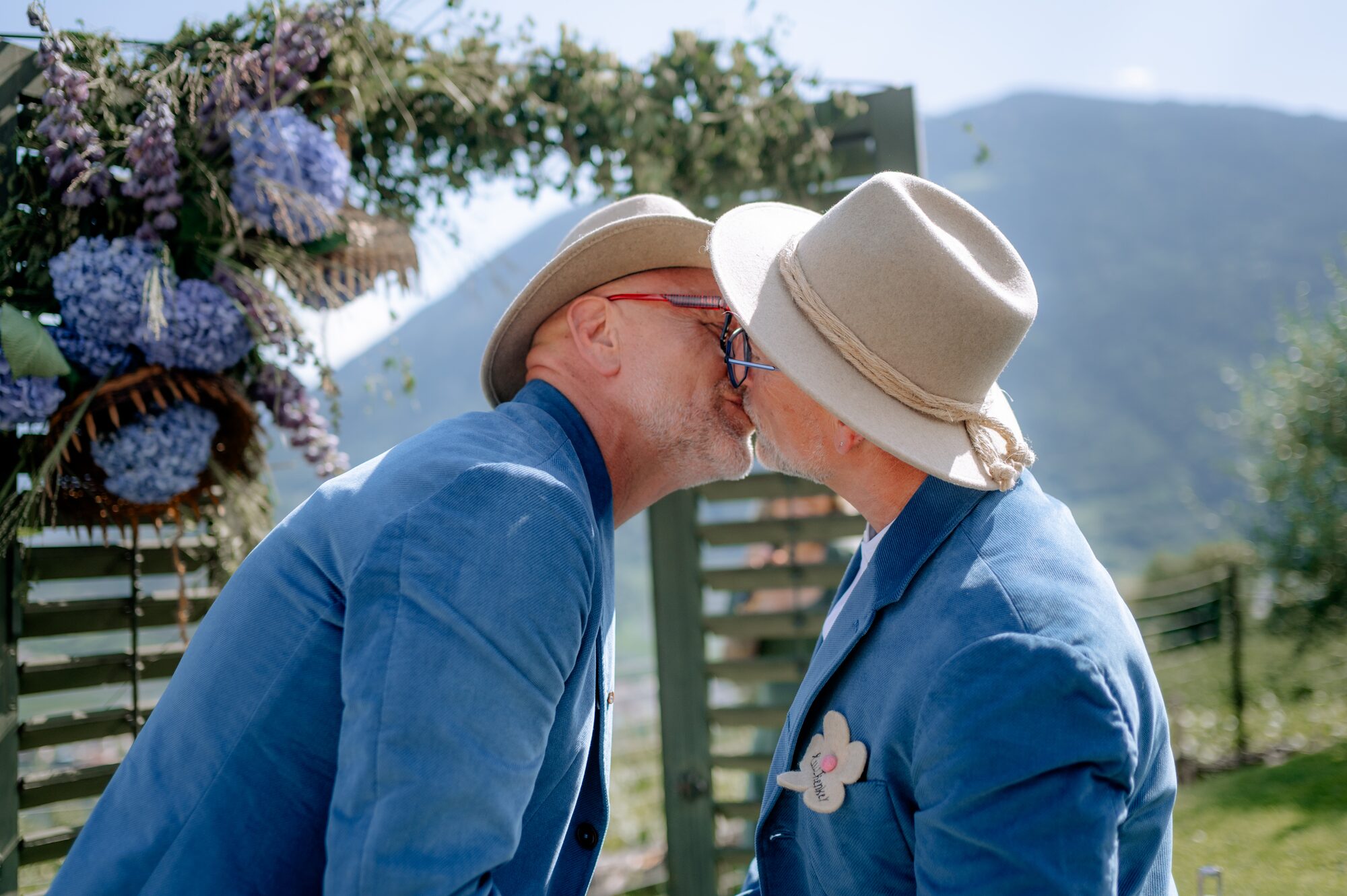 Thorsten Rausch und Ingmar Laimer küssen sich nach dem Ja-Wort unter dem Blumenbogen ihrer Hochzeit in Südtirol