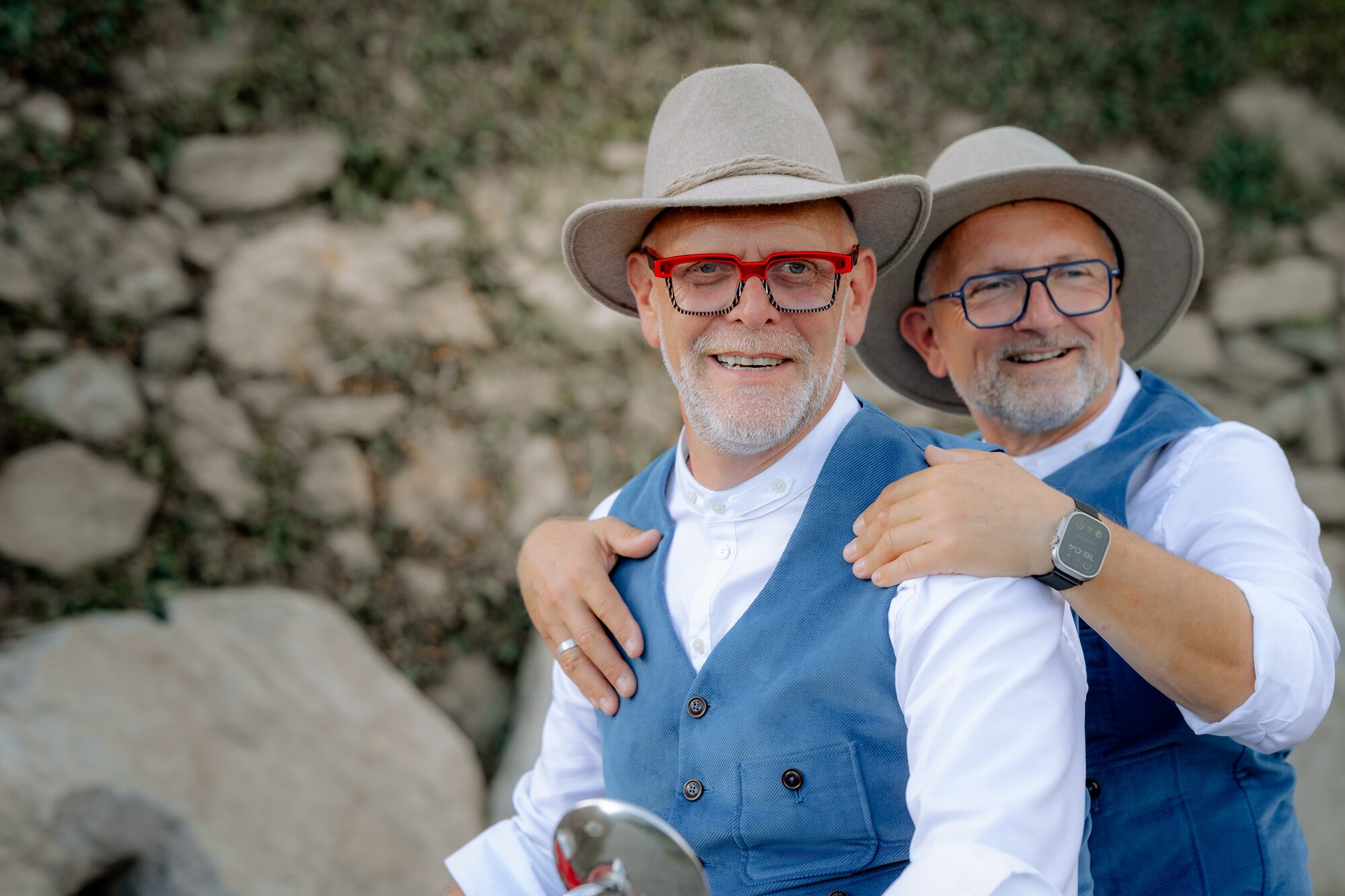 Paarportrait von Thorsten Rausch und Ingmar Laimer, die sich vor einer Trockenmauer im Weinberg umarmen