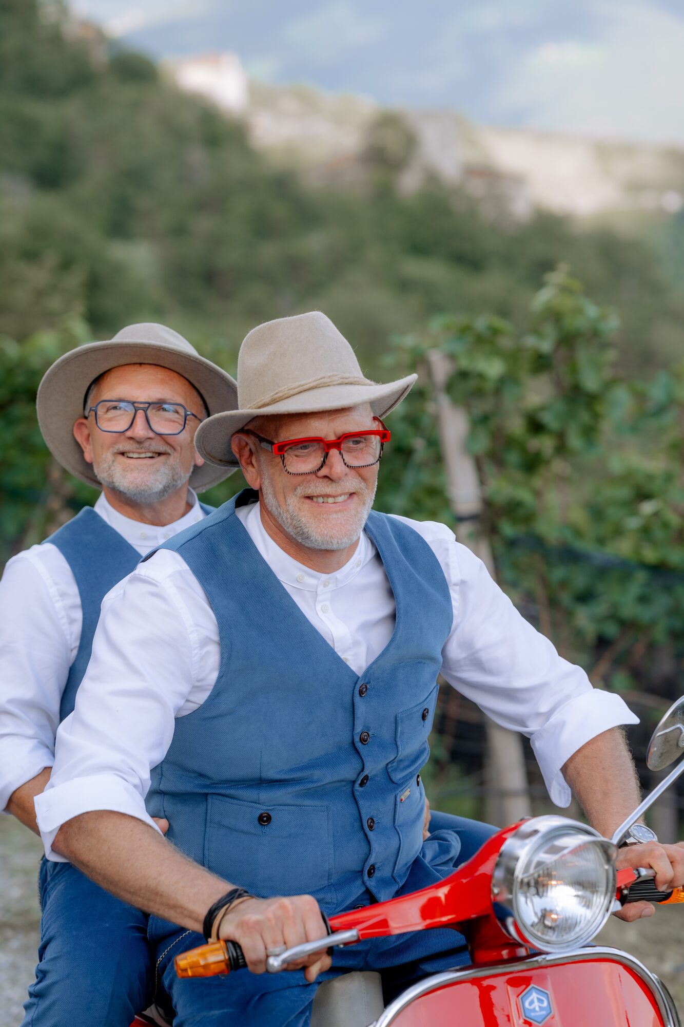 Thorsten Rausch und Ingmar Laimer sitzen nach ihrer Hochzeit in Südtirol gemeinsam auf einer roten Vespa